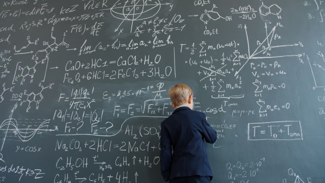 pets lower blood pressure. Young boy in suit writing on chalkboard with formulas